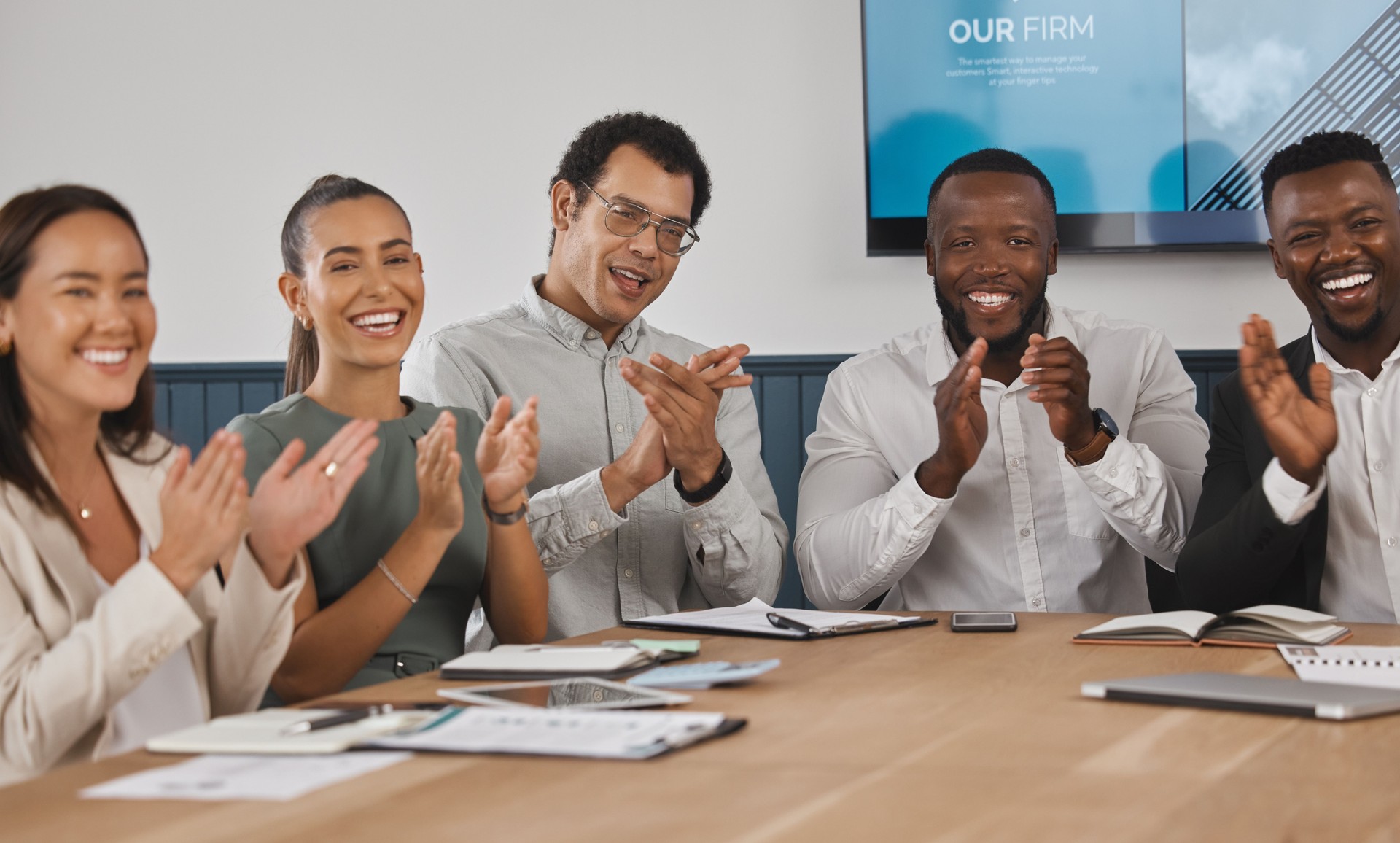 Un grupo de jóvenes empresarios corporativos diversos y confiados aplaudiendo mientras están sentados en la sala de juntas durante una reunión de trabajo. Celebrando el éxito y la promoción de un compañero de trabajo. Estamos felices por ti
